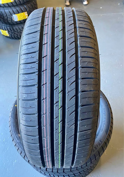 Close-up of a car tire with tread pattern on a light blue surface